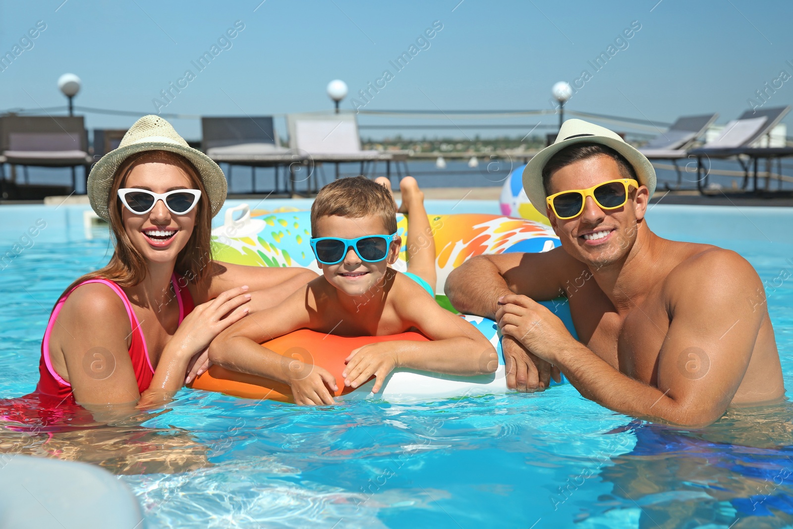 Photo of Happy family with inflatable ring in swimming pool