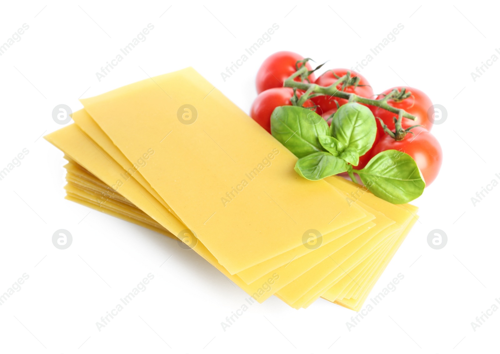 Photo of Uncooked lasagna sheets, tomatoes and basil on white background