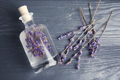 Flat lay composition with natural herbal oil and lavender flowers on wooden background