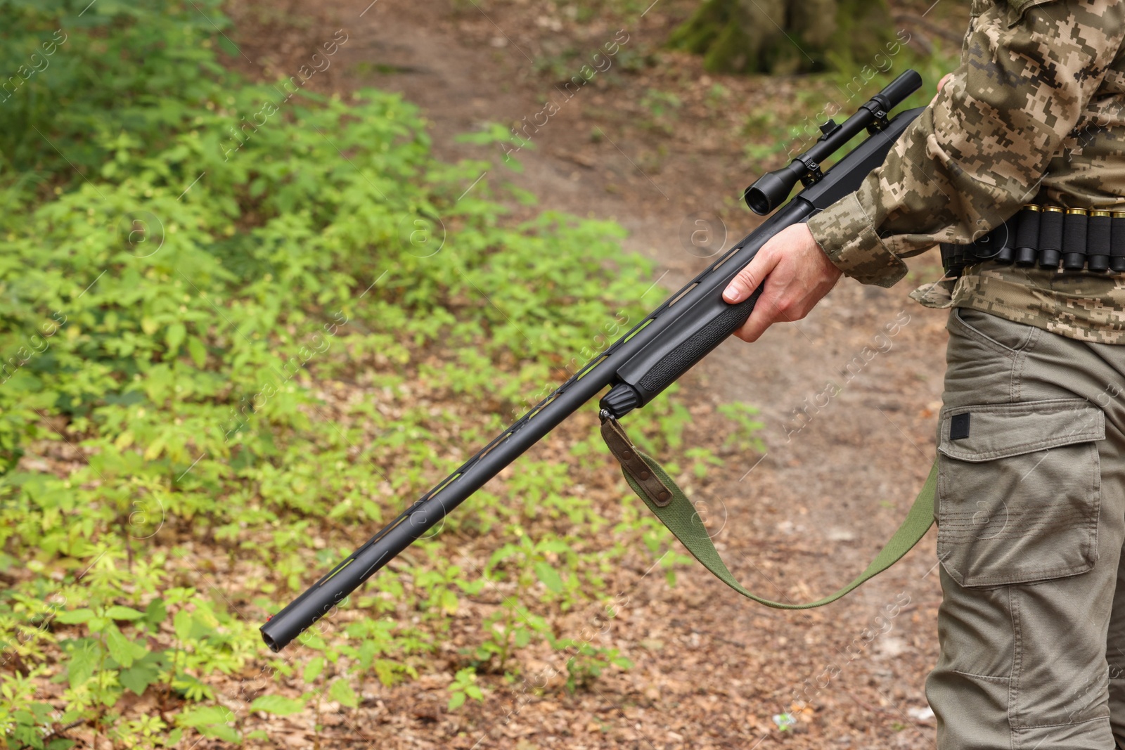 Photo of Man with hunting rifle wearing camouflage in forest, closeup
