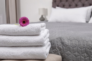 Photo of Stack of fresh towels on bedside bench in hotel room