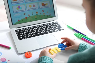 Little girl learning English indoors at online lesson, closeup