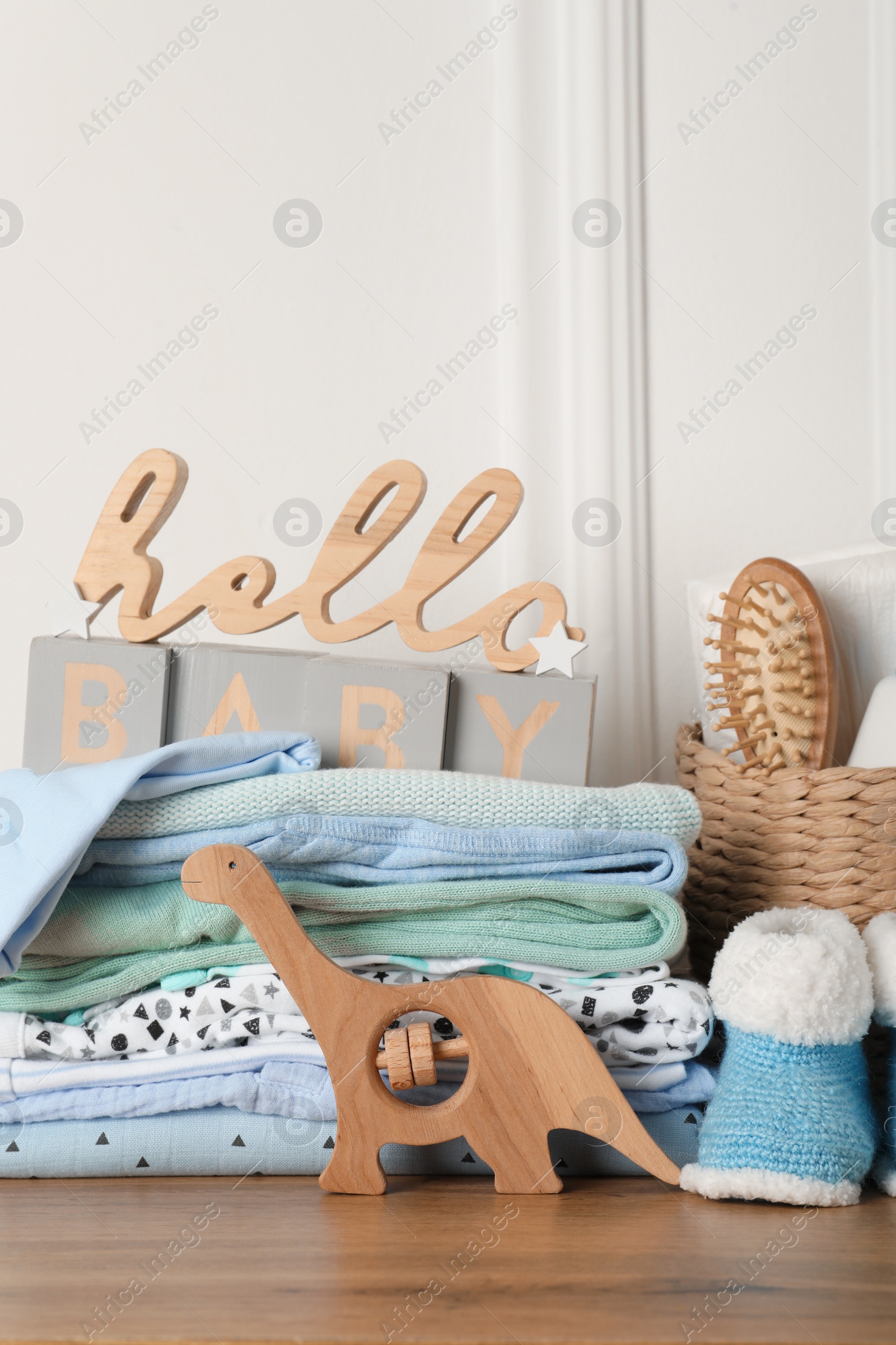 Photo of Baby clothes, toy and accessories on wooden table