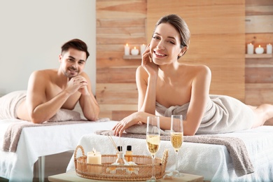 Photo of Romantic young couple with champagne in spa salon