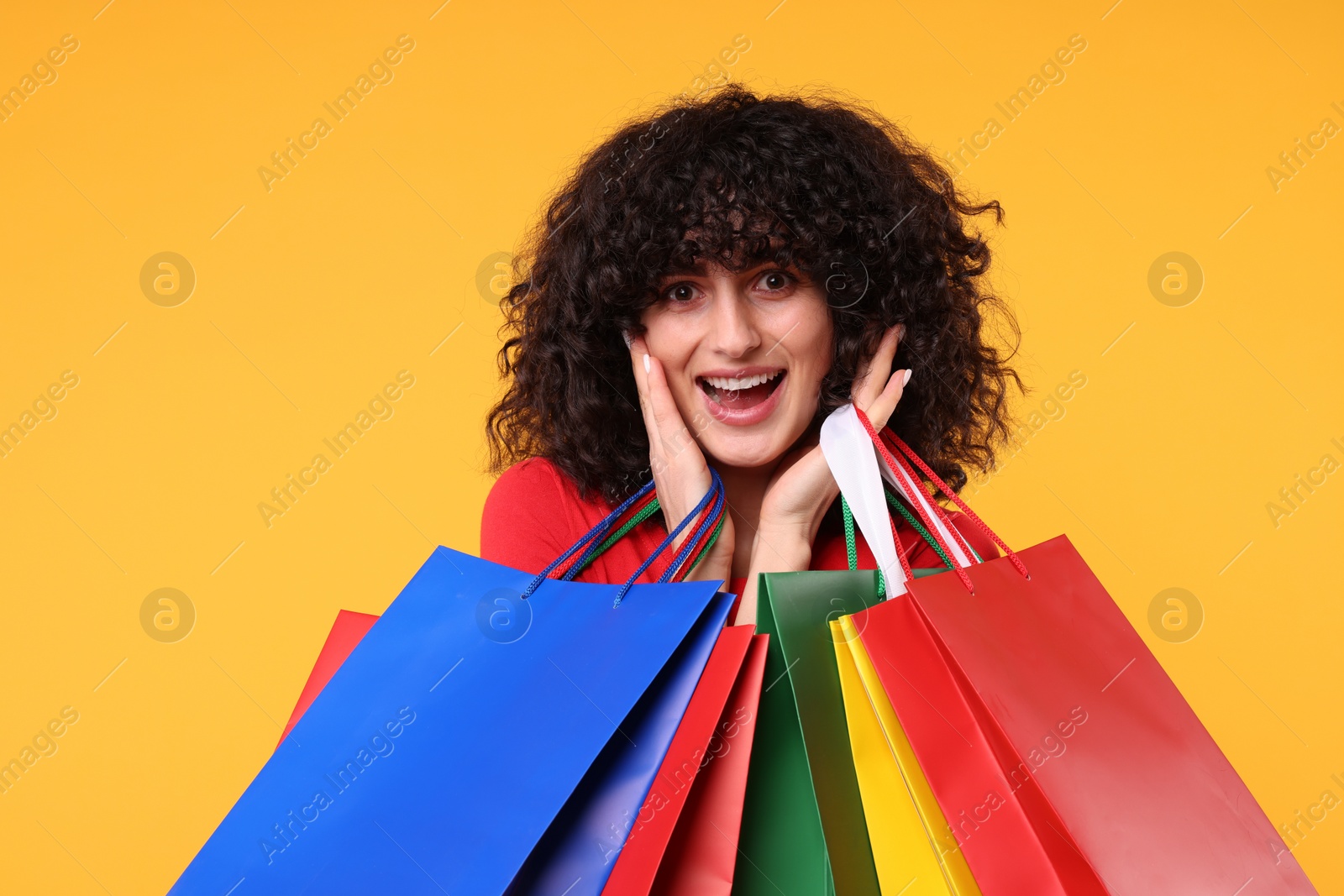 Photo of Happy young woman with shopping bags on yellow background