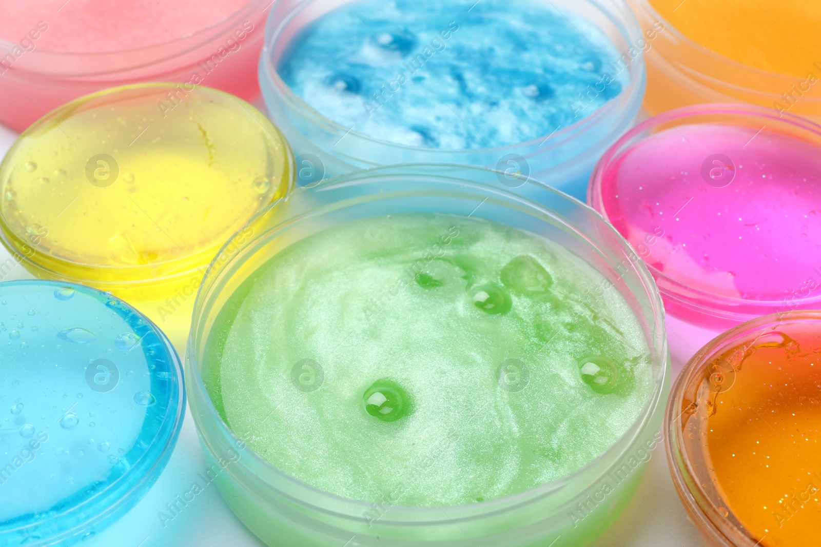 Photo of Colorful slimes in plastic containers, closeup. Antistress toy