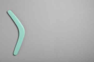 Photo of Turquoise wooden boomerang on grey background, top view. Space for text