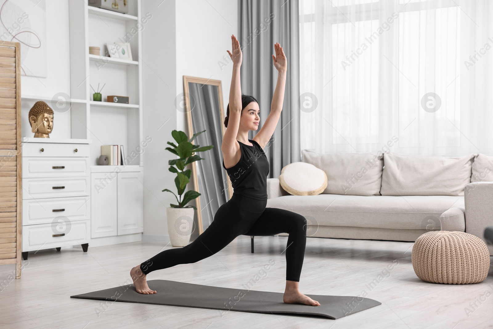 Photo of Girl practicing crescent asana on yoga mat at home. High lunge pose