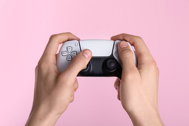 Photo of Man using wireless game controller on pink background, closeup