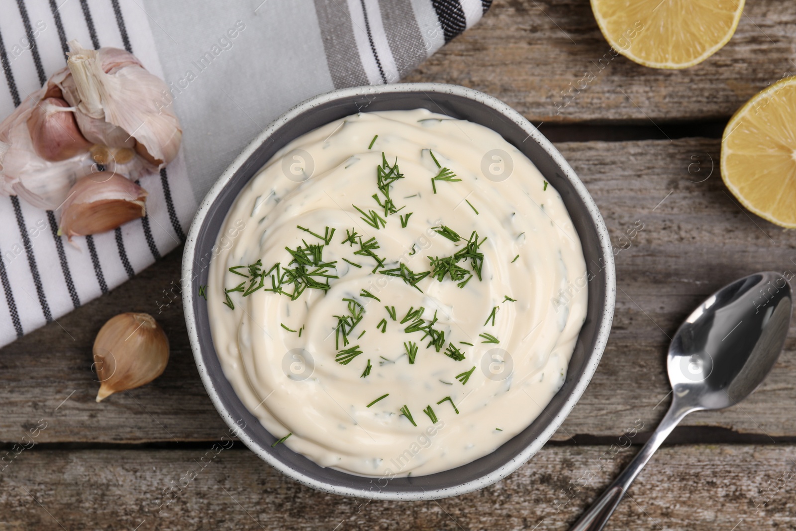 Photo of Tasty creamy dill sauce and ingredients on wooden table, flat lay