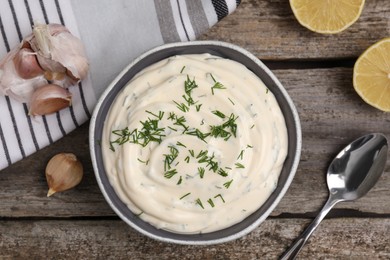 Tasty creamy dill sauce and ingredients on wooden table, flat lay