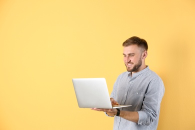 Photo of Young man with laptop on color background