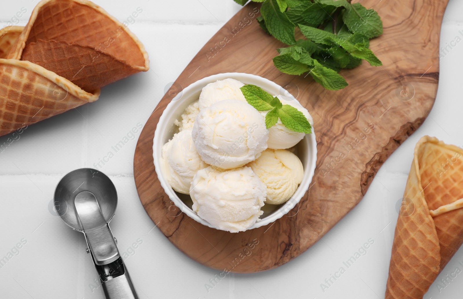 Photo of Bowl of ice cream, cones and mint leaves on white table, flat lay