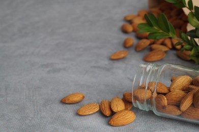 Photo of Jar with delicious almonds on grey table, closeup. Space for text