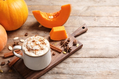 Photo of Cup with tasty pumpkin spice latte and space for text on wooden table