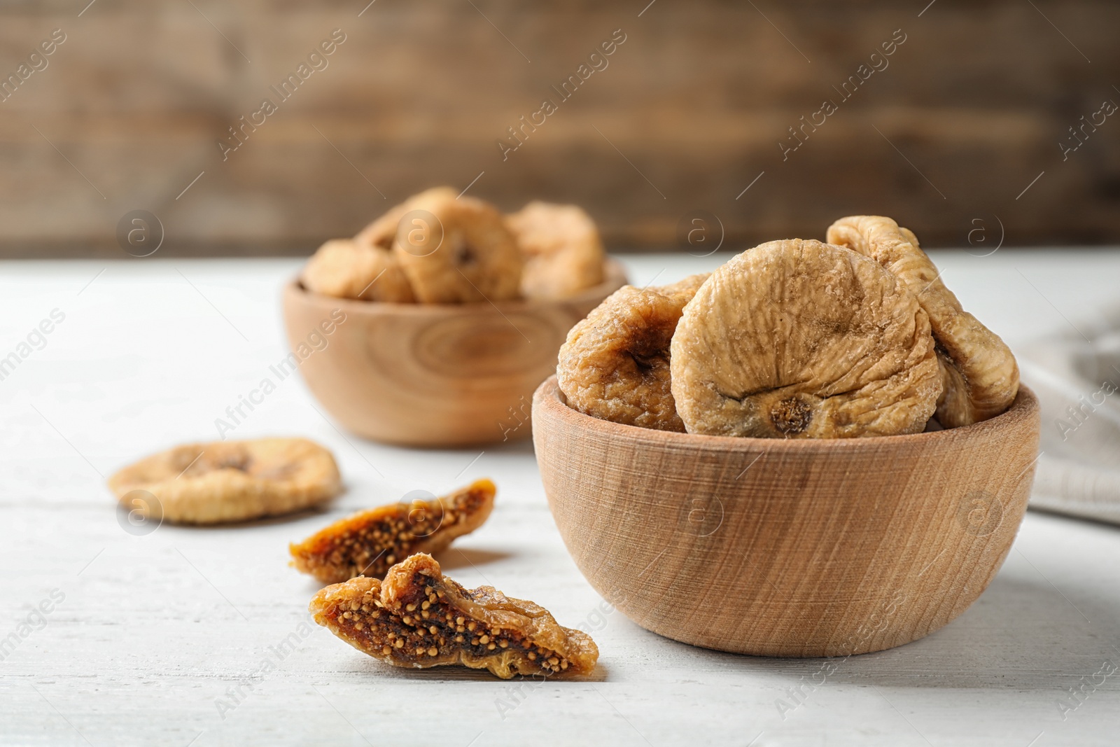 Photo of Wooden bowl of tasty dried figs on white table. Space for text