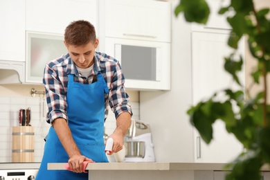 Photo of Man cleaning table with rag in kitchen
