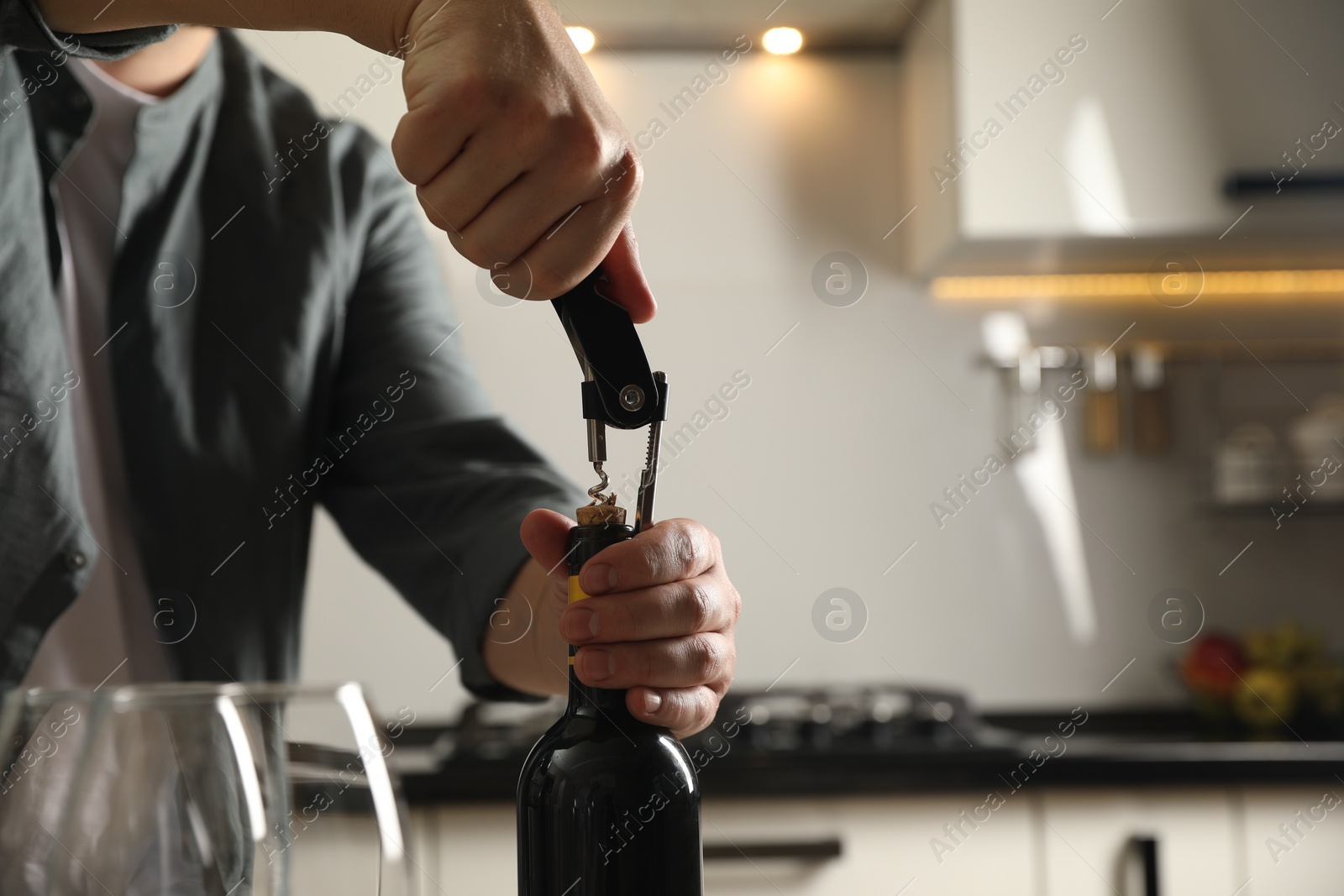 Photo of Man opening wine bottle with corkscrew indoors, closeup. Space for text