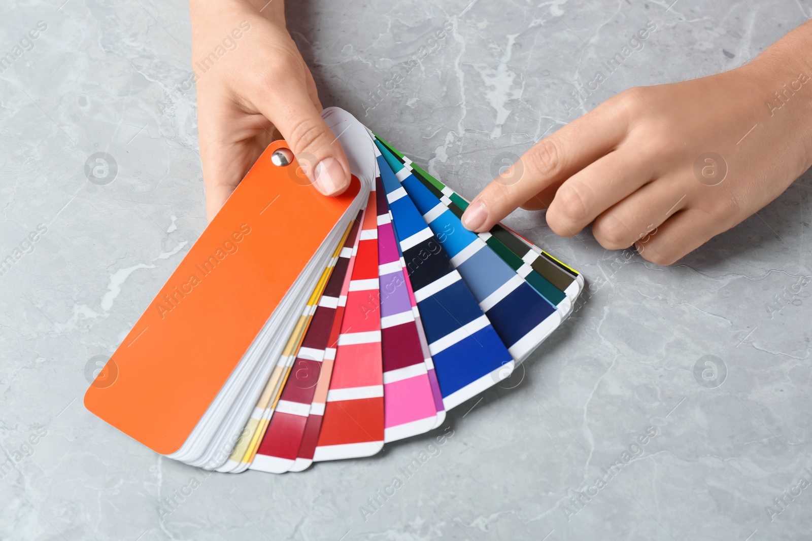 Photo of Woman with palette samples at grey marble table, closeup