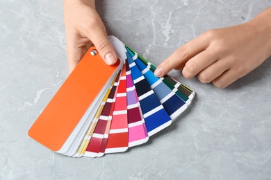 Photo of Woman with palette samples at grey marble table, closeup