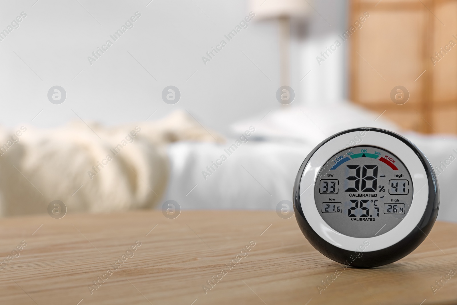 Photo of Digital hygrometer with thermometer on wooden table indoors. Space for text