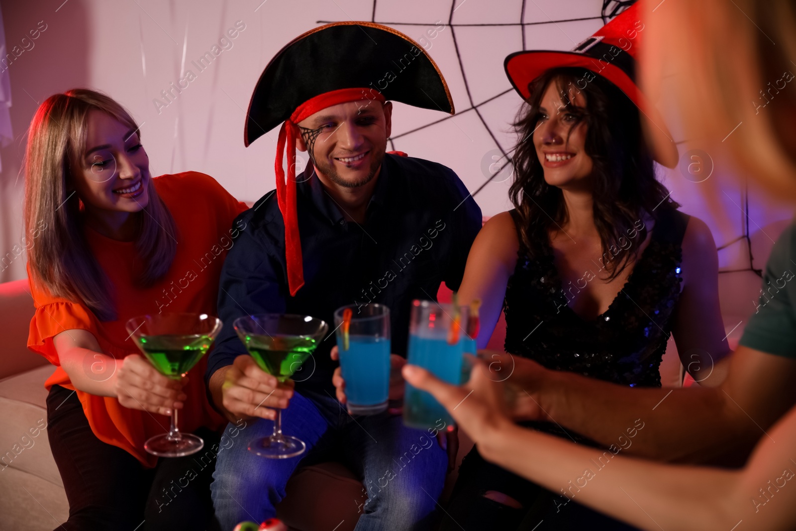 Photo of Group of friends toasting with cocktails at Halloween party indoors