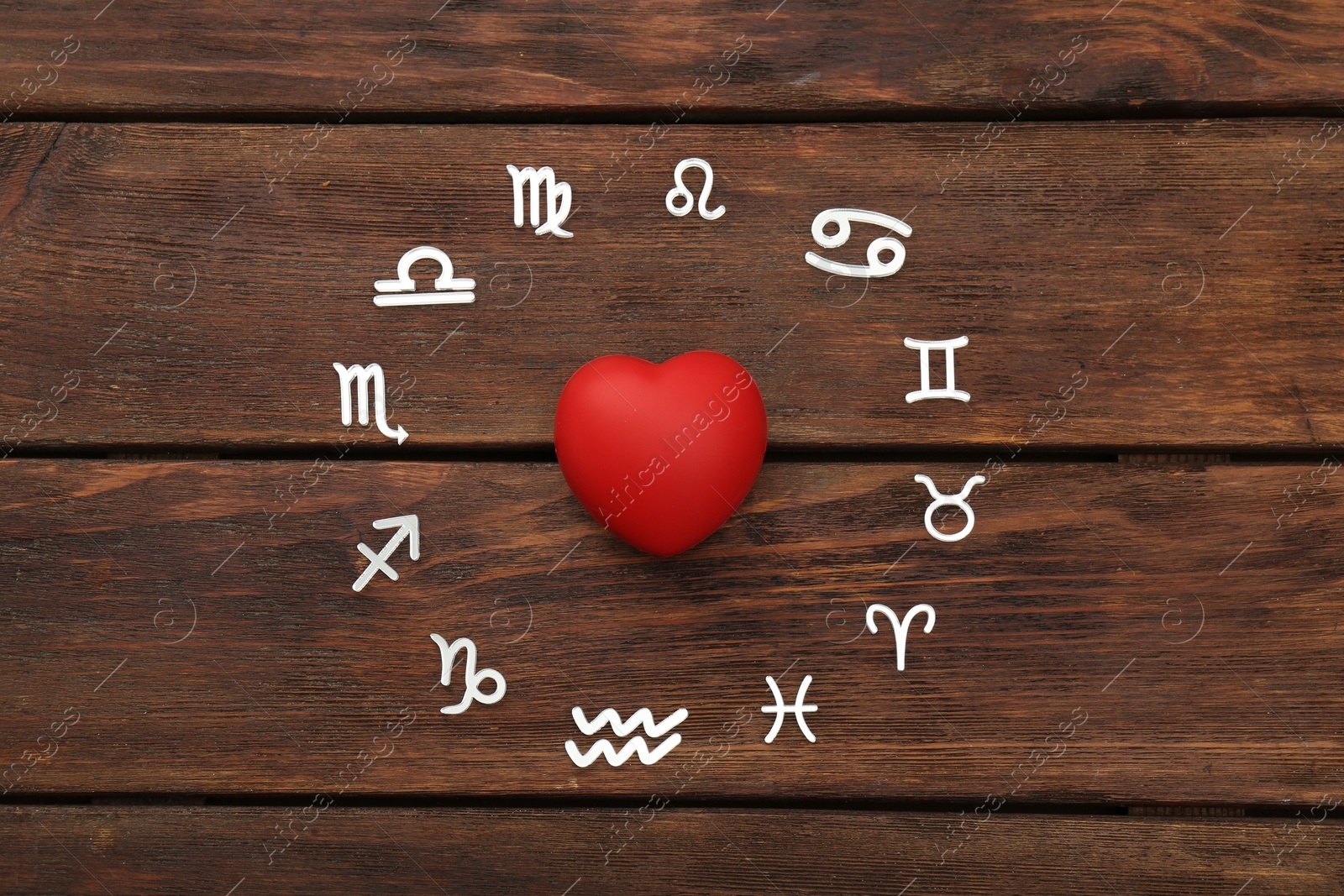 Photo of Zodiac signs and red heart on wooden background, flat lay