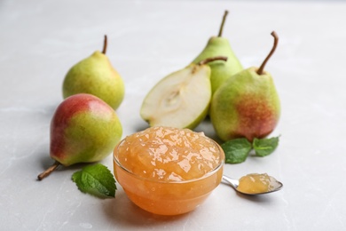 Photo of Delicious pear jam and fresh fruits on light grey table