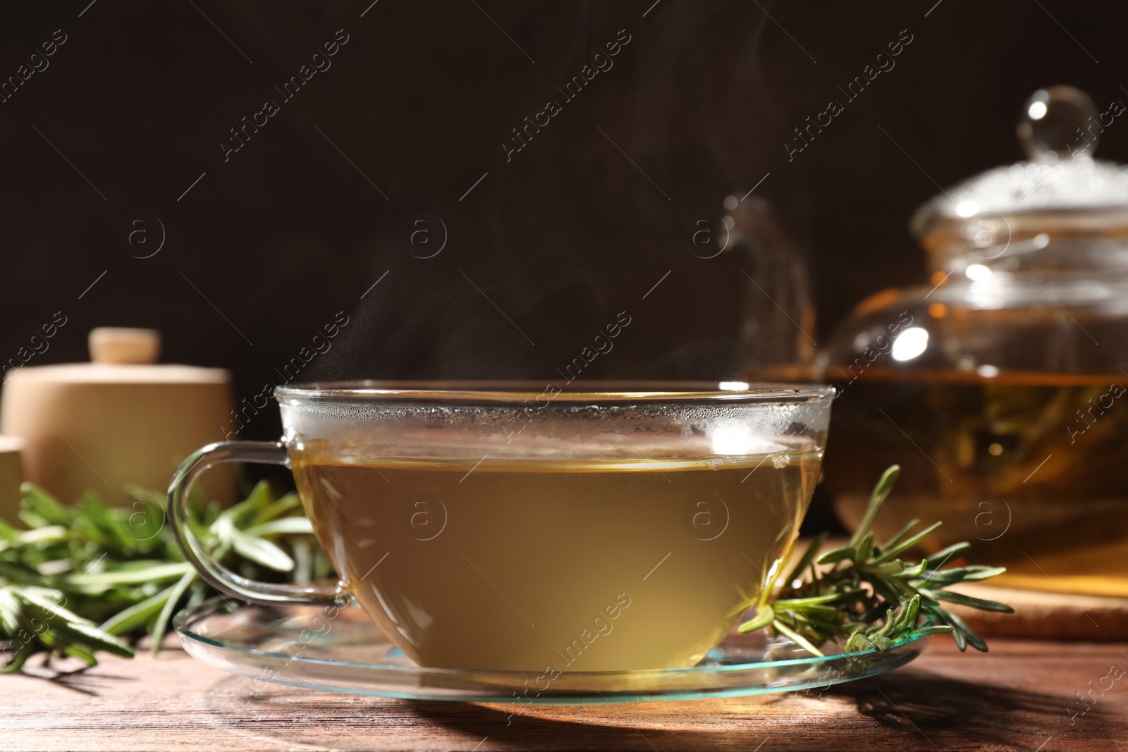 Photo of Cup of aromatic herbal tea and fresh rosemary on wooden table