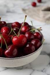 Photo of Fresh ripe cherries with water drops in bowl on white marble table, closeup