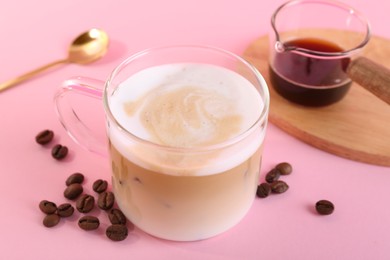 Cup of fresh coffee and beans on pink table, closeup