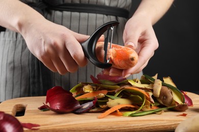 Photo of Woman peeling fresh carrot at table, closeup