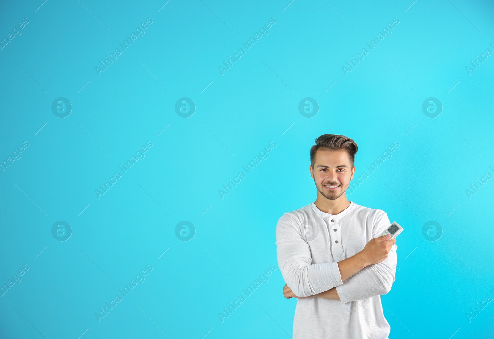 Photo of Young man with air conditioner remote on color background