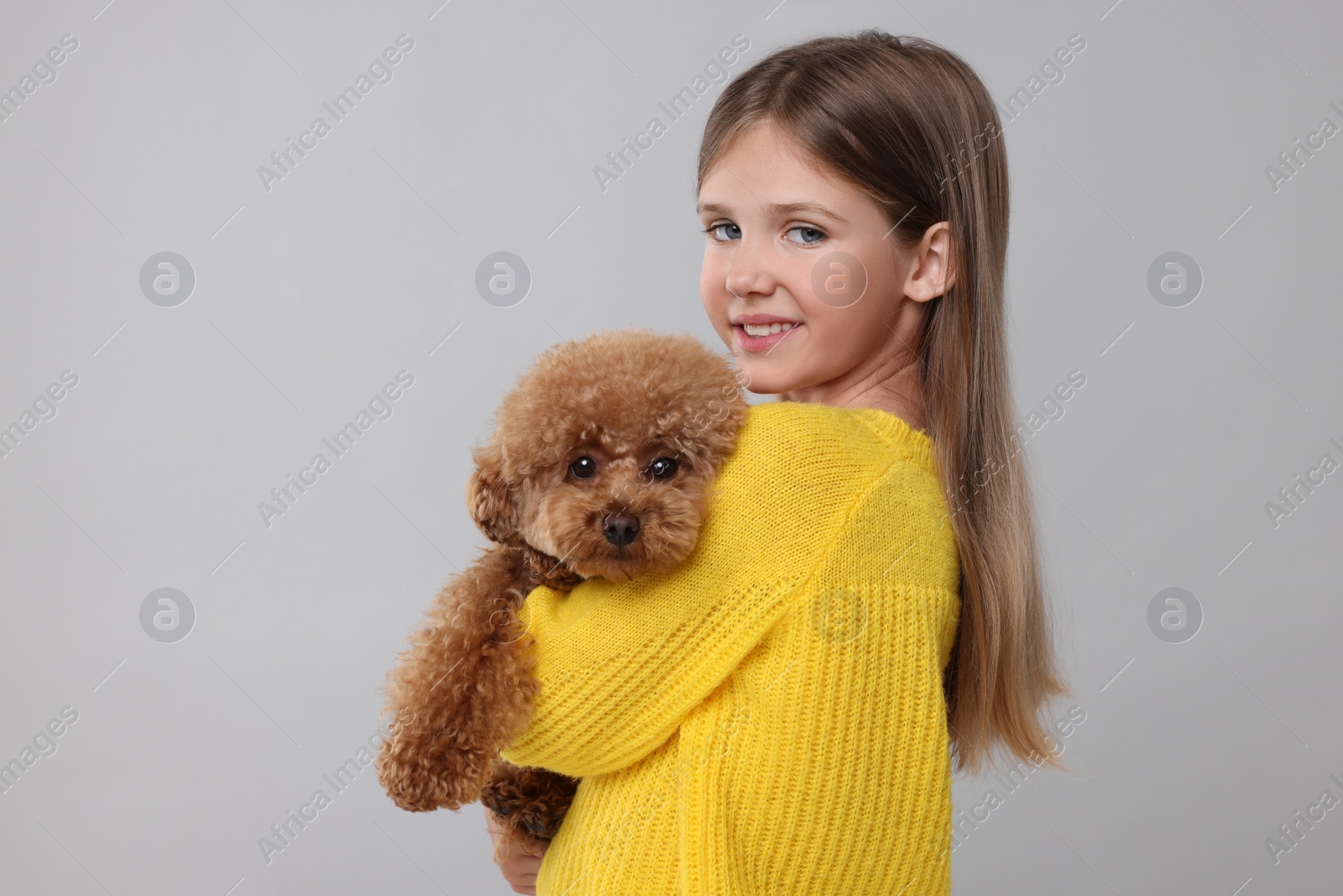 Photo of Little child with cute puppy on light grey background. Lovely pet