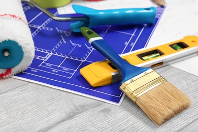 Photo of Set with decorator tools and apartment plan on wooden background