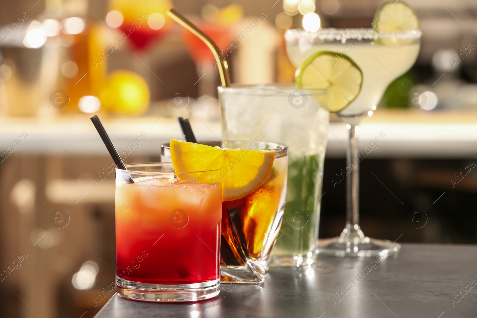 Photo of Different delicious cocktails on grey table in bar