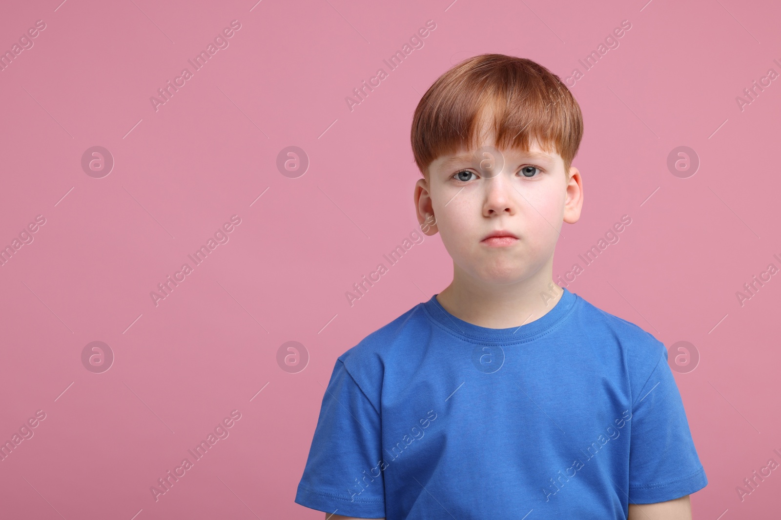 Photo of Portrait of sad little boy on pink background, space for text