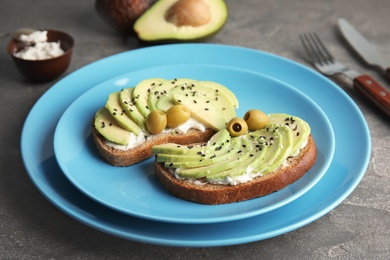 Photo of Crisp rye toasts with avocado, cream cheese and olives on plate, closeup