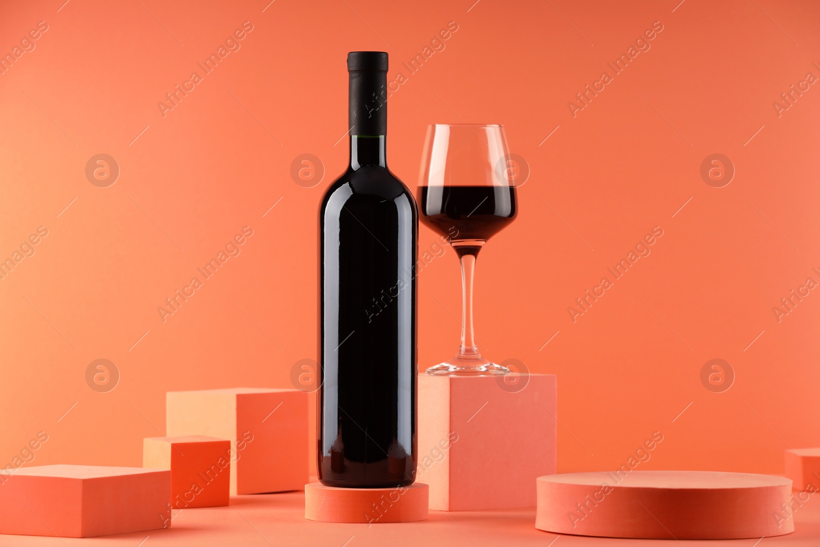 Photo of Stylish presentation of delicious red wine in bottle and glass on orange background