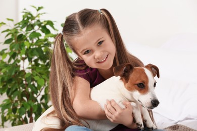 Cute girl hugging her dog indoors. Adorable pet