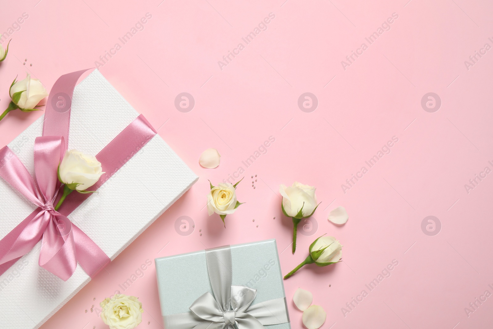 Photo of Elegant gift boxes and beautiful flowers on pink background, flat lay. Space for text