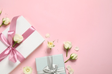 Photo of Elegant gift boxes and beautiful flowers on pink background, flat lay. Space for text