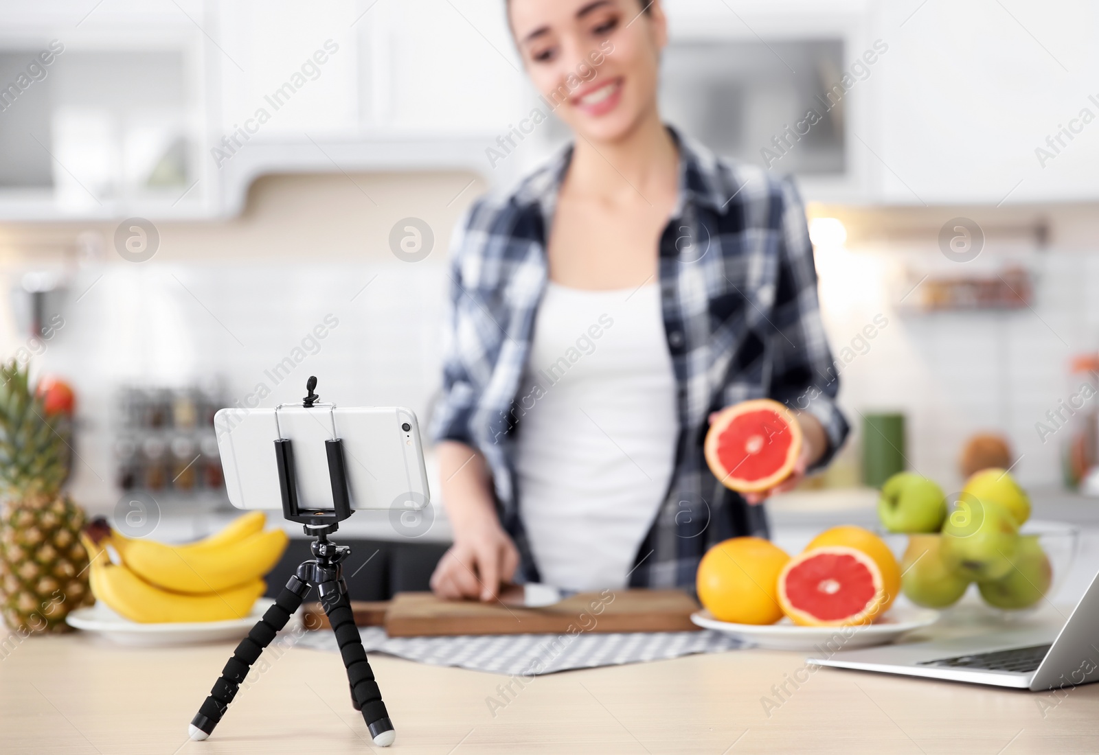 Photo of Young blogger with fruits recording video on kitchen