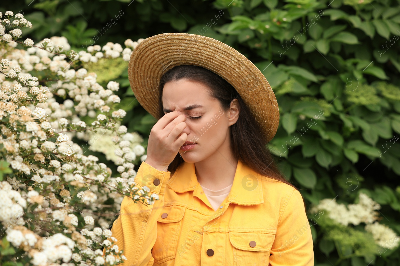 Photo of Woman suffering from seasonal pollen allergy near blossoming tree on spring day