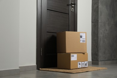 Cardboard boxes on floor mat near entrance. Parcel delivery service
