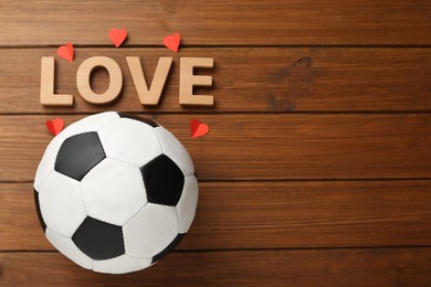 Soccer ball, hearts and word Love on wooden background, flat lay. Space for text