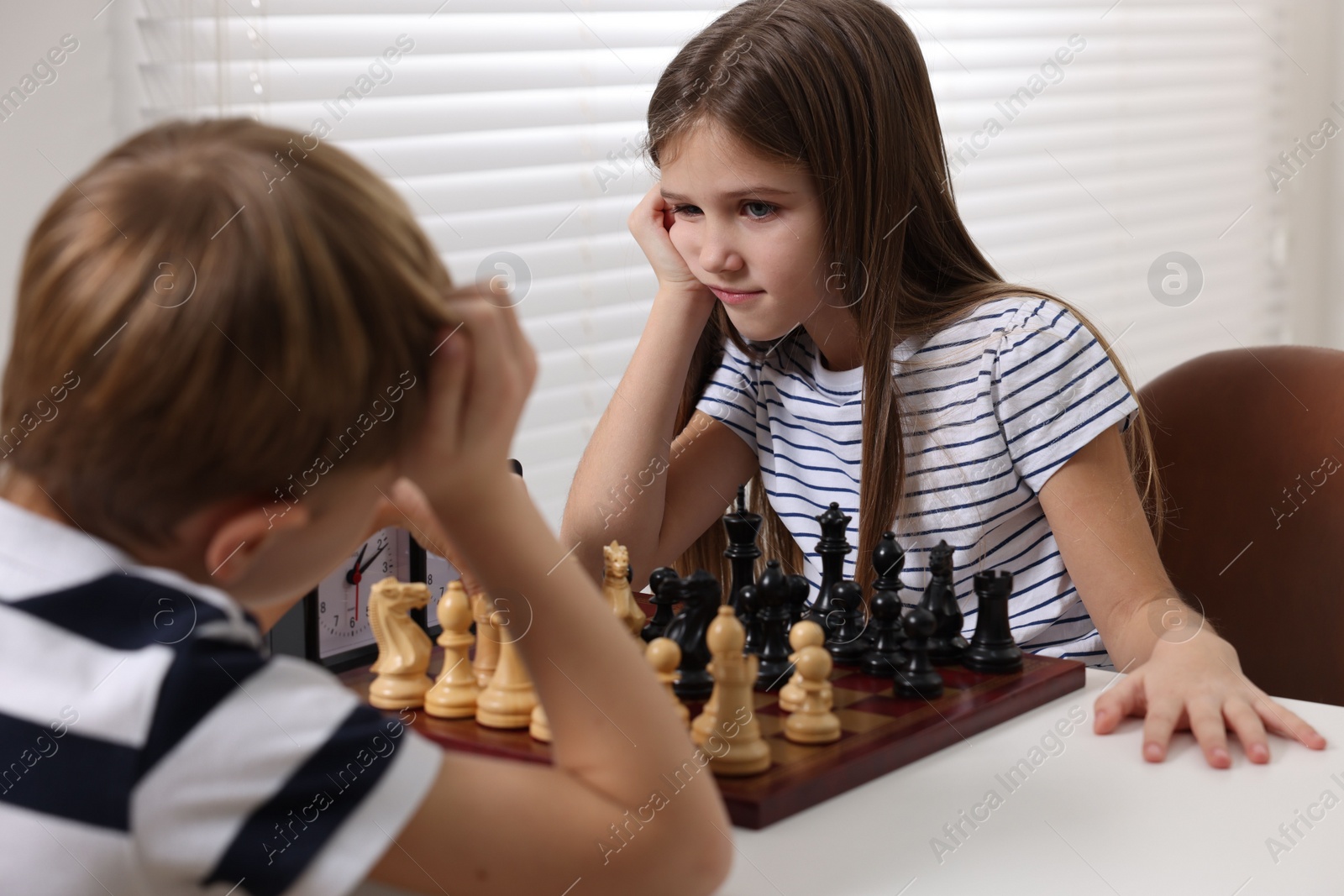 Photo of Cute children playing chess at table in room