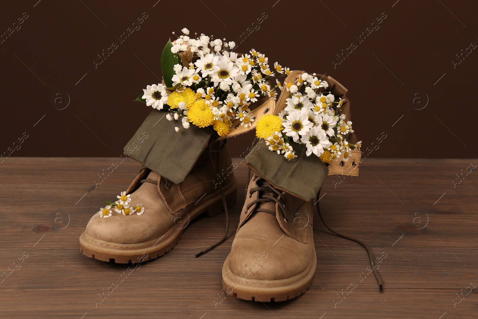 Photo of Boots with beautiful flowers on wooden surface