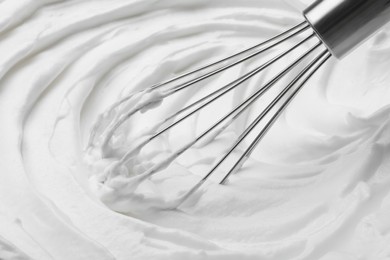Photo of Whipping white cream with balloon whisk, closeup view