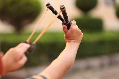 Photo of Little boy playing with slingshot outdoors, closeup